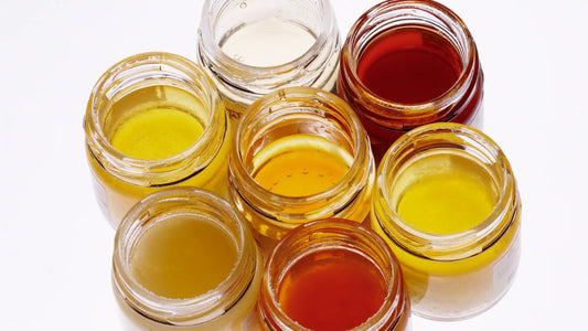 Assortiment de pots de miel artisaux issus de différentes fleurs avec variations de couleurs et textures
